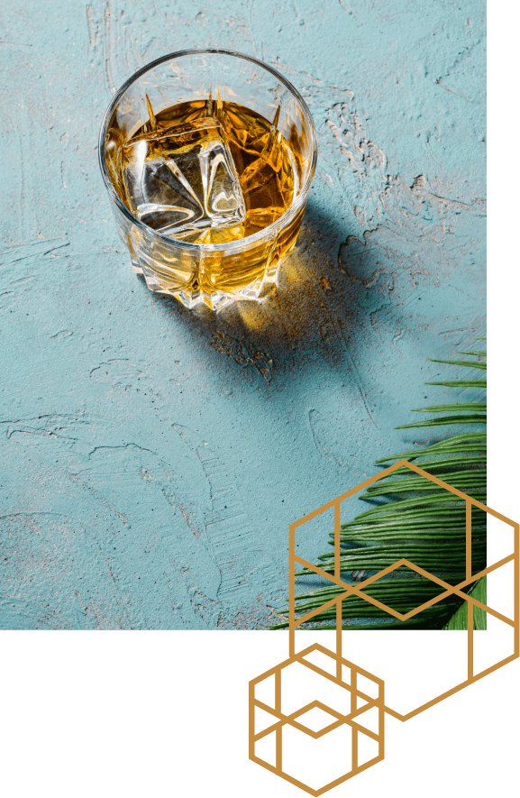 Glass of amber colored liquor being chilled by a single cube of Block Ice.